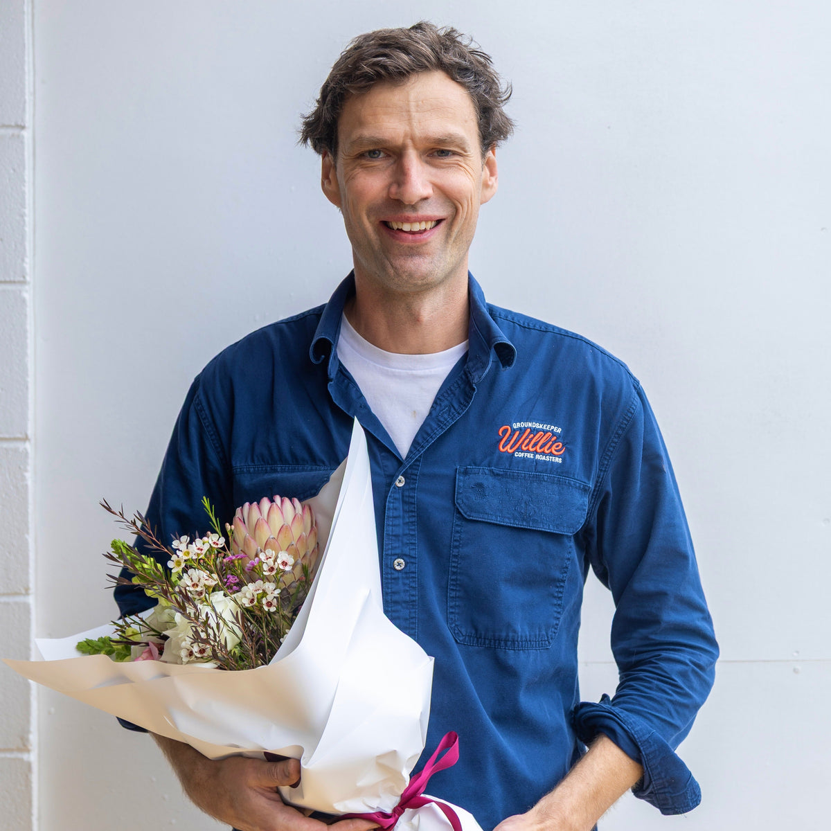 Signature series bouquet of flowers including natives and whites against a white wall
