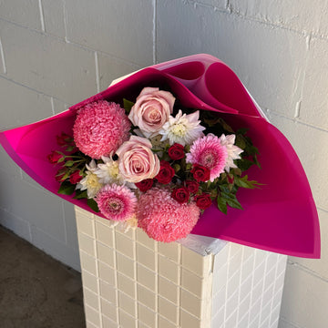 Bouquet of flowers for valentines day 
wrapped in pink paper on a tiled floor.